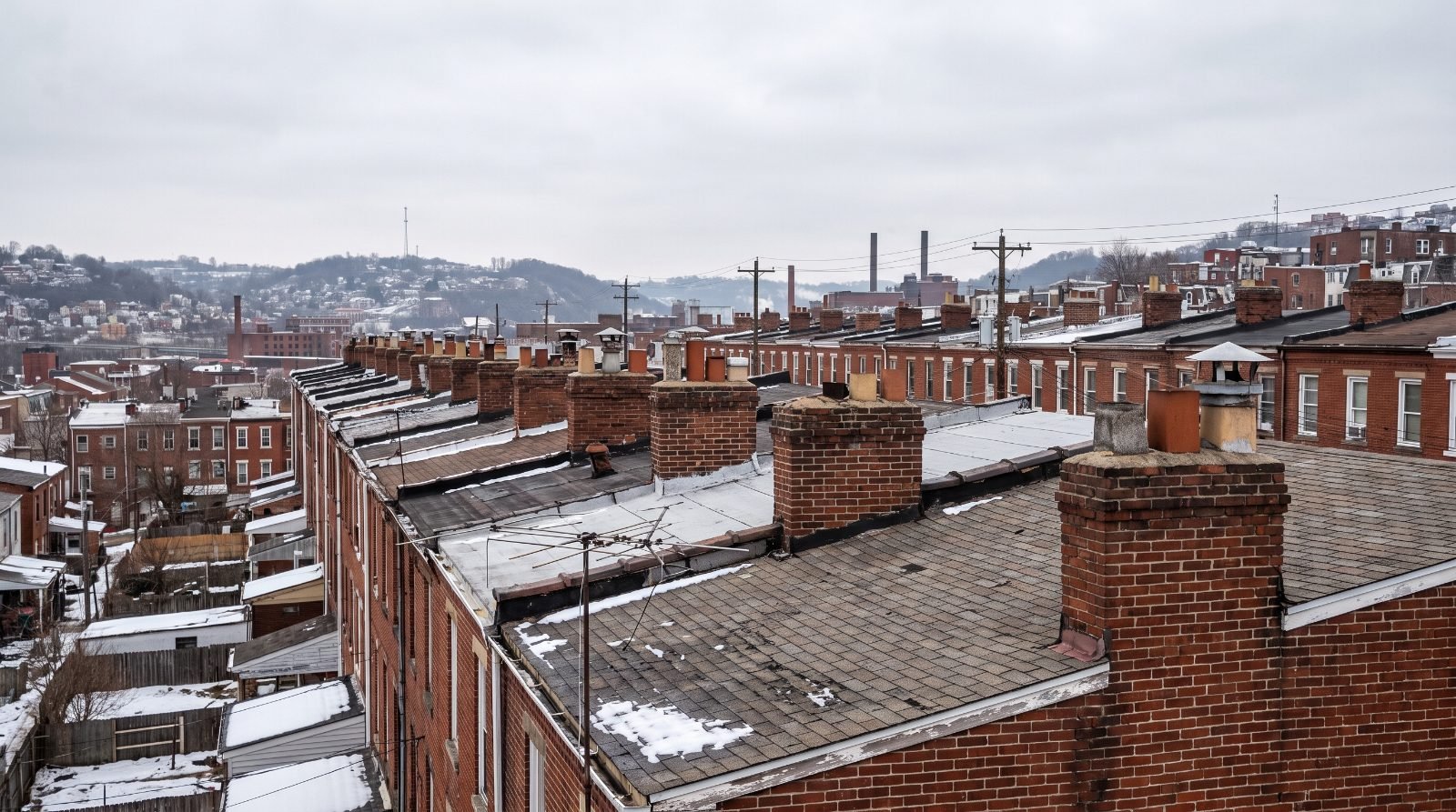Row of brick chimneys along attached rooftops in an older Pittsburgh neighbourhood